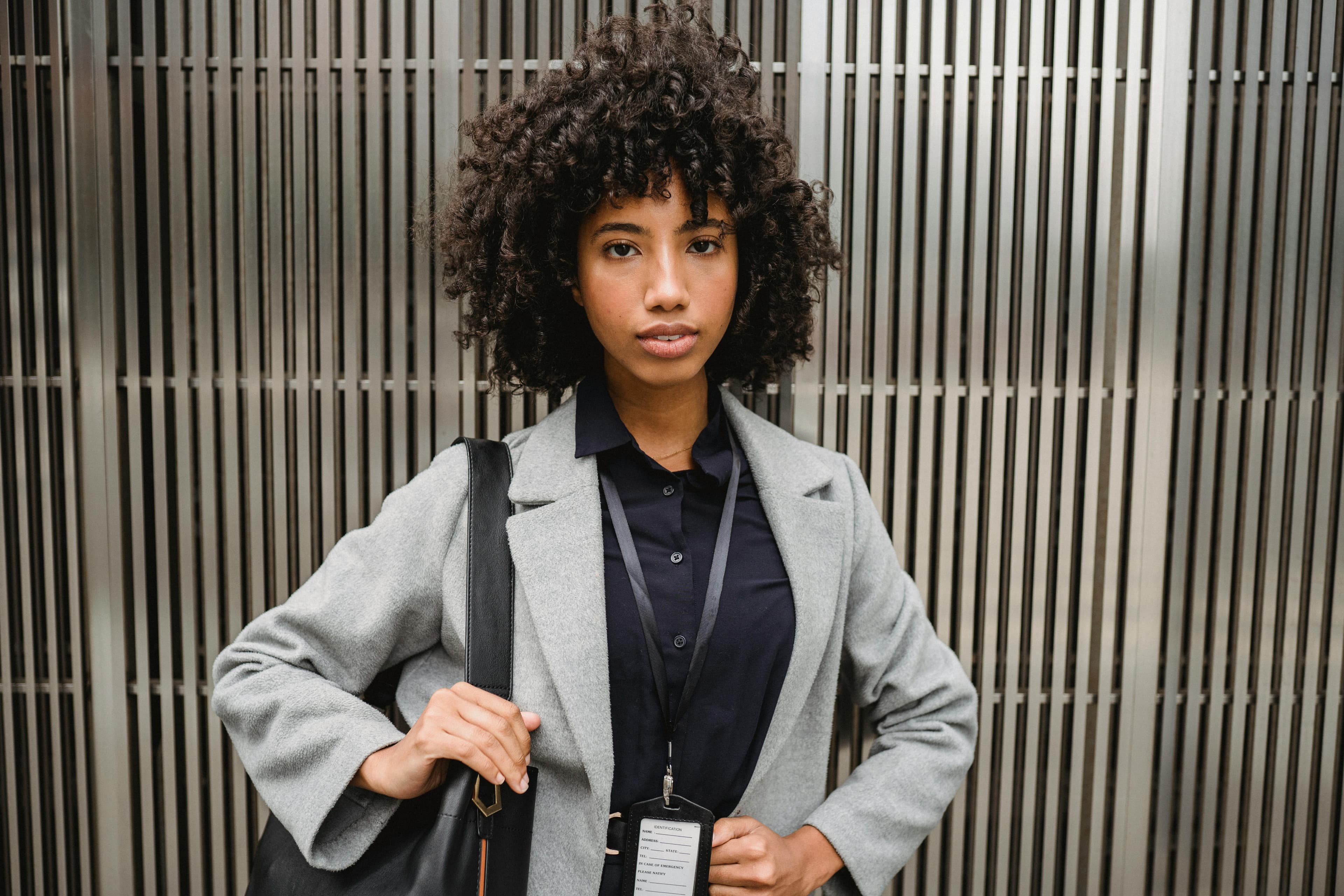 A professional holding an identification card on a lanyard in front of a metal facade