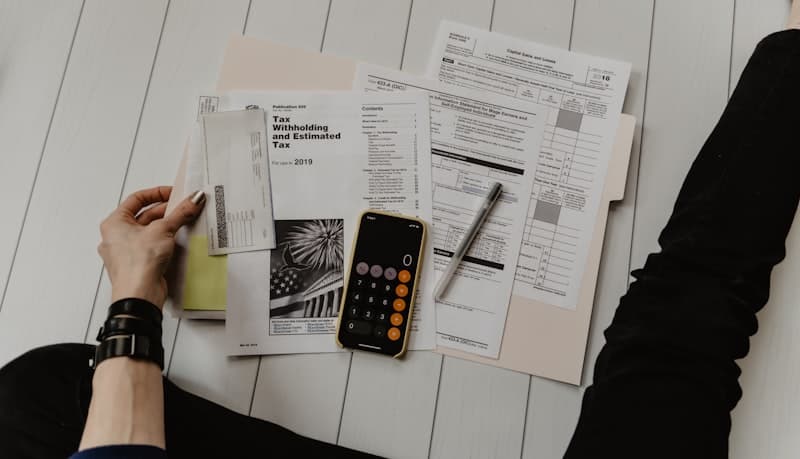 Person reviewing tax and background check documents spread on a table